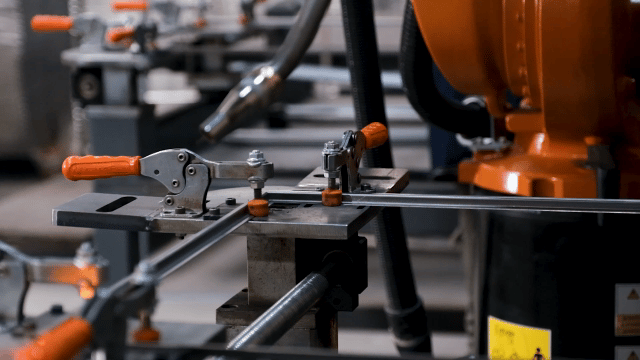 The industrial robotic arm approaches the metal part.