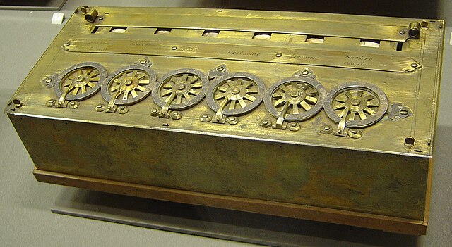 Pascal's mechanical calculator: a brass box-shaped machine with six numbered wheels on the top, displaying results in six small windows.