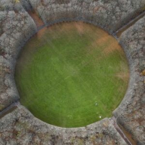 Overhead view of a circular field surrounded by trees.