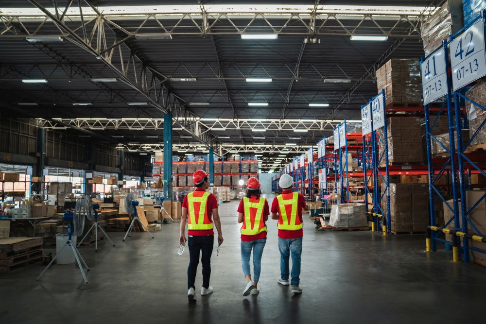 Large warehouse with high shelves. Workers are walking to check materials on the shelves.